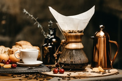 白色的陶瓷茶杯旁边面包和咖啡壶
